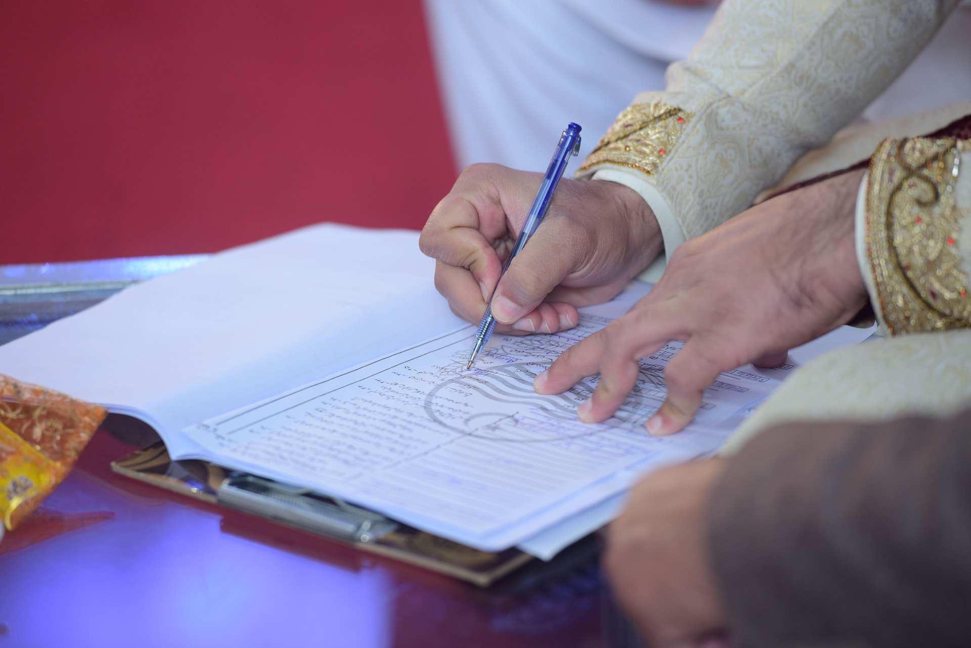 Hands signing a Nikah marriage contract in Urdu script