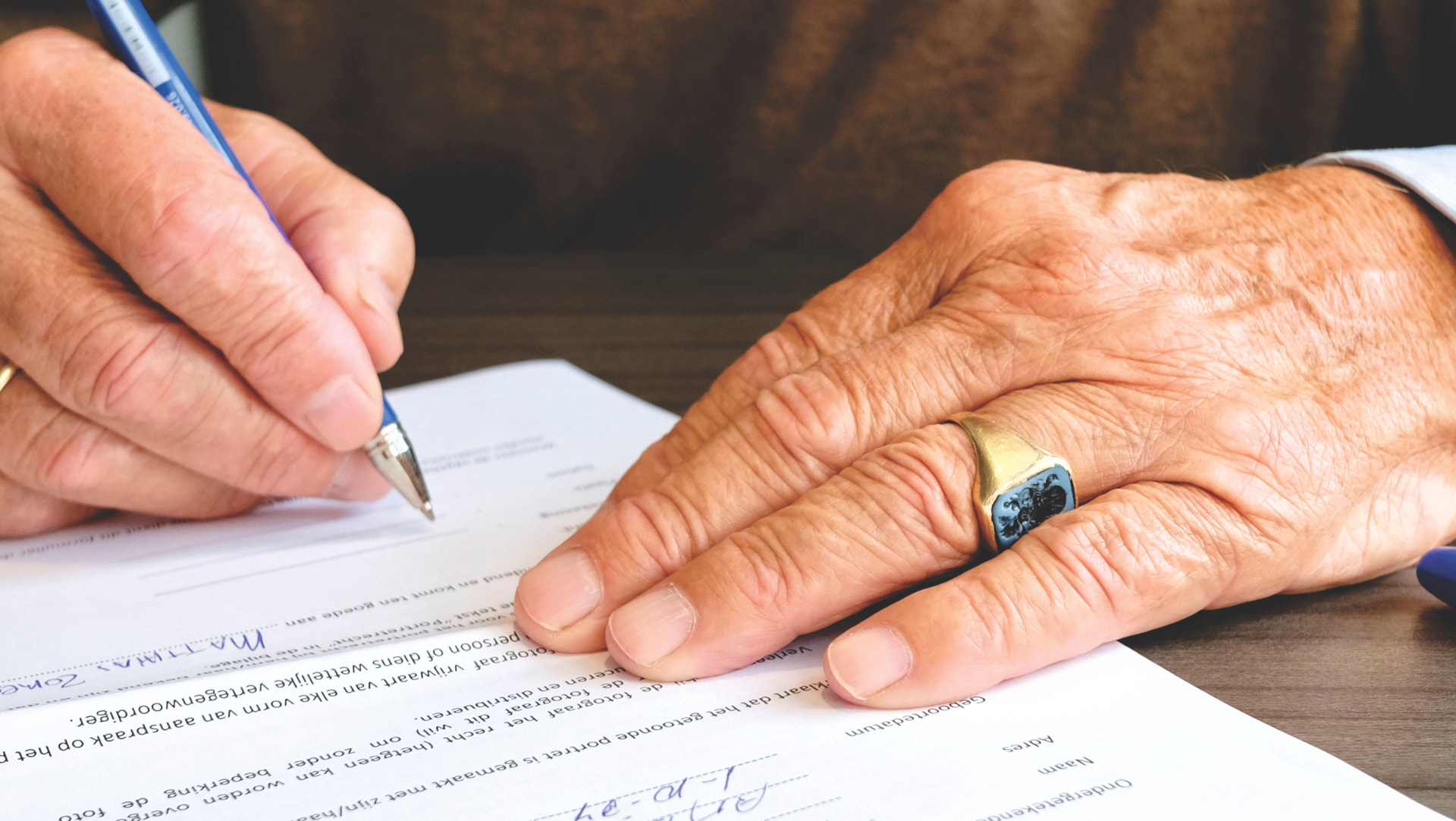 An elderly client signing a power of attorney with a blue pen
